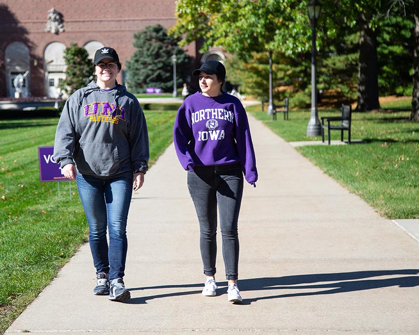 UNI students wearing purple and gold walking through central campus