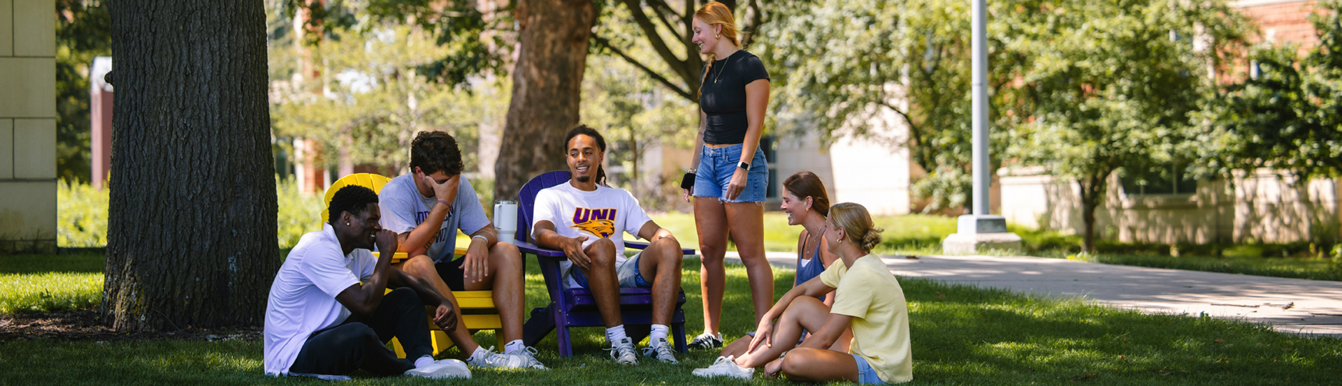 A group of students gather outside Panther Village in adirondack chairs