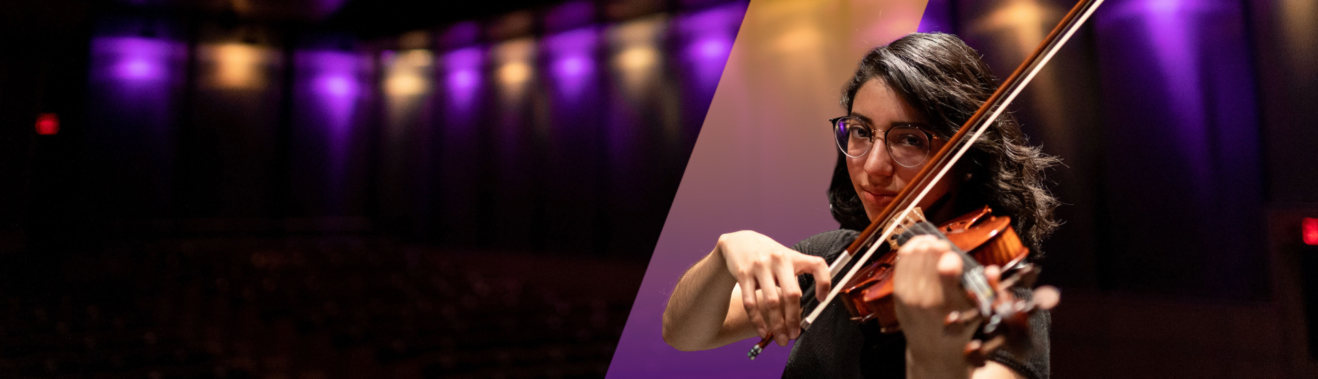 A female student playing the violin with purple and gold lights behind her.