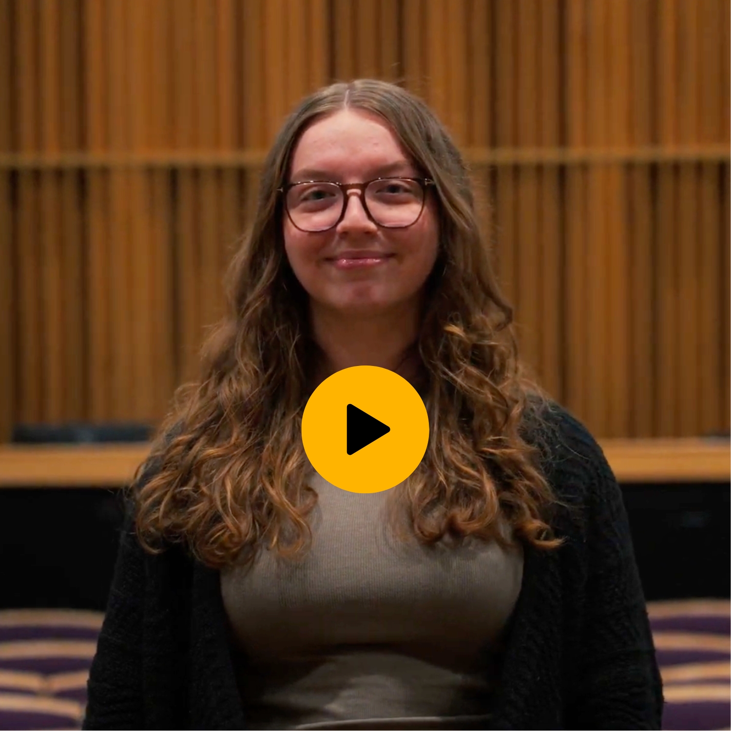 Lilly Kallengerger smiling at the camera with a yellow play button in the middle.