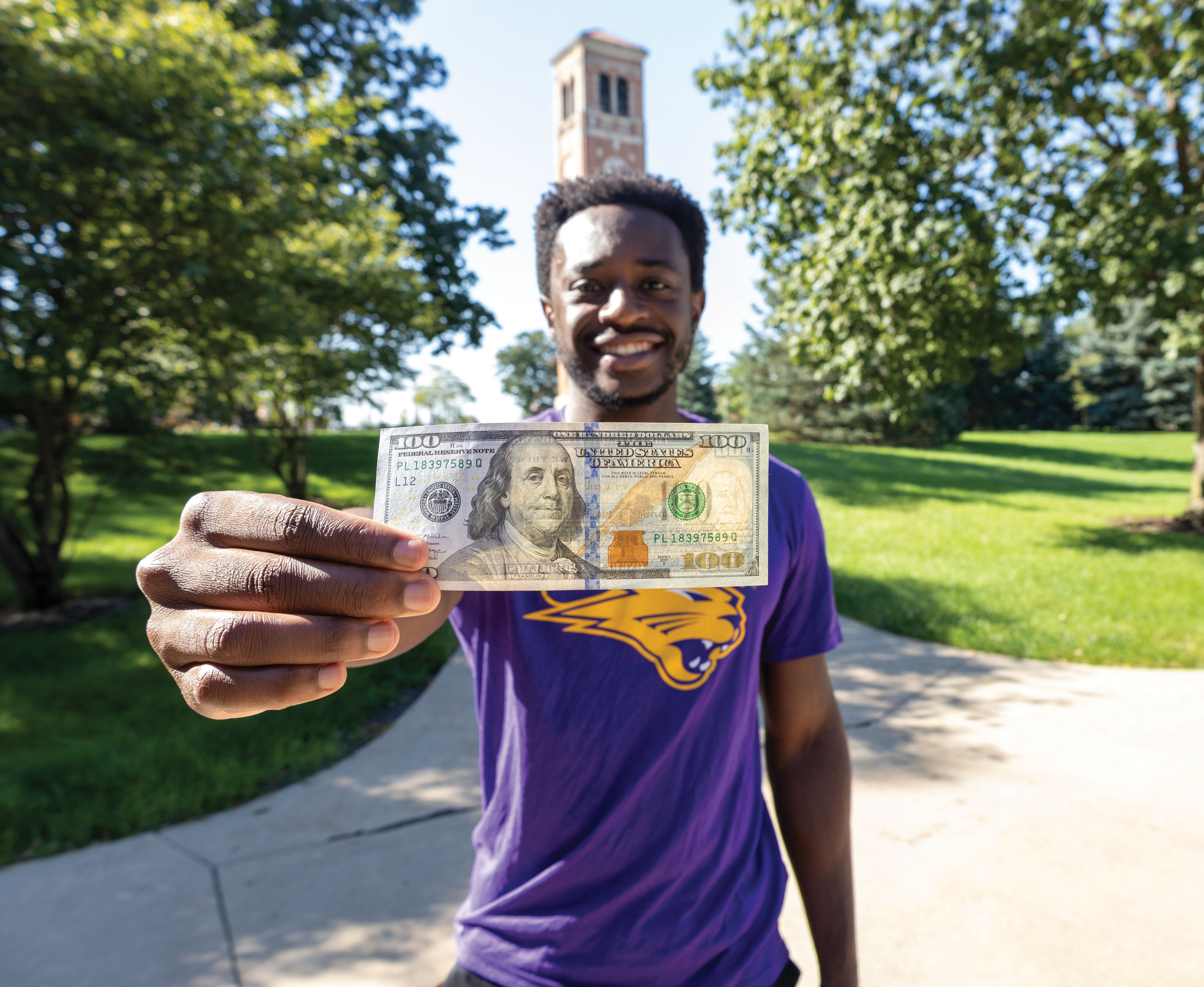 UNI student holding up a $100 bill.