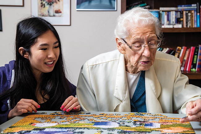 UNI gerontology student building a puzzle with an elderly woman