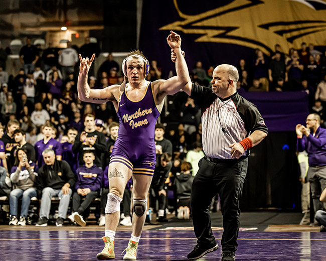 UNI wrestler in the West Gym with his hands raised after a victory