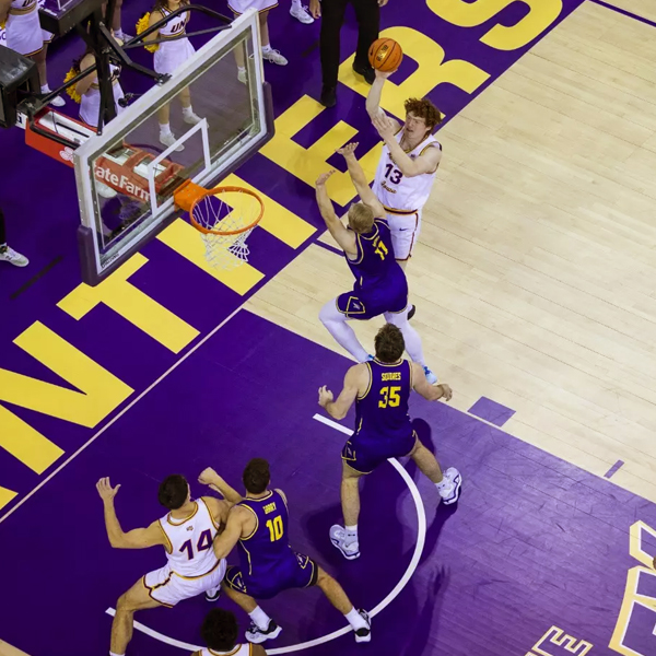 An aerial shot of UNI men's basketball players taking it to the hoop during a game.