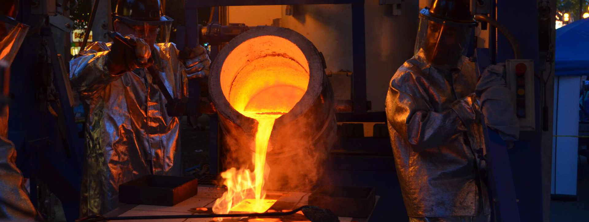 Molten liquid is being poured from a metal casting foundry