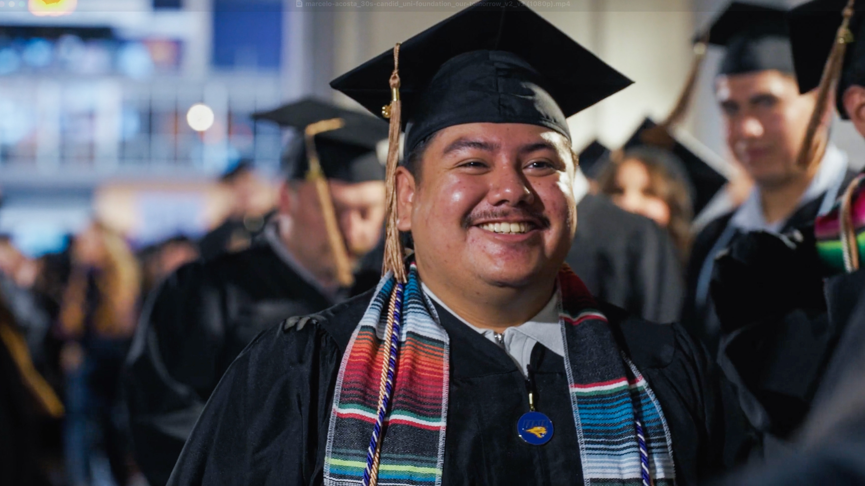 UNI student Marcelo Acosta smiling at graduation with a cap and gown.