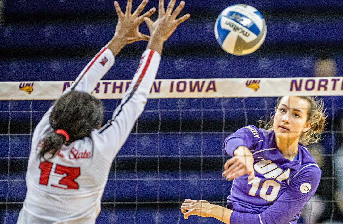 UNI Volleyball player smacking the ball over the net